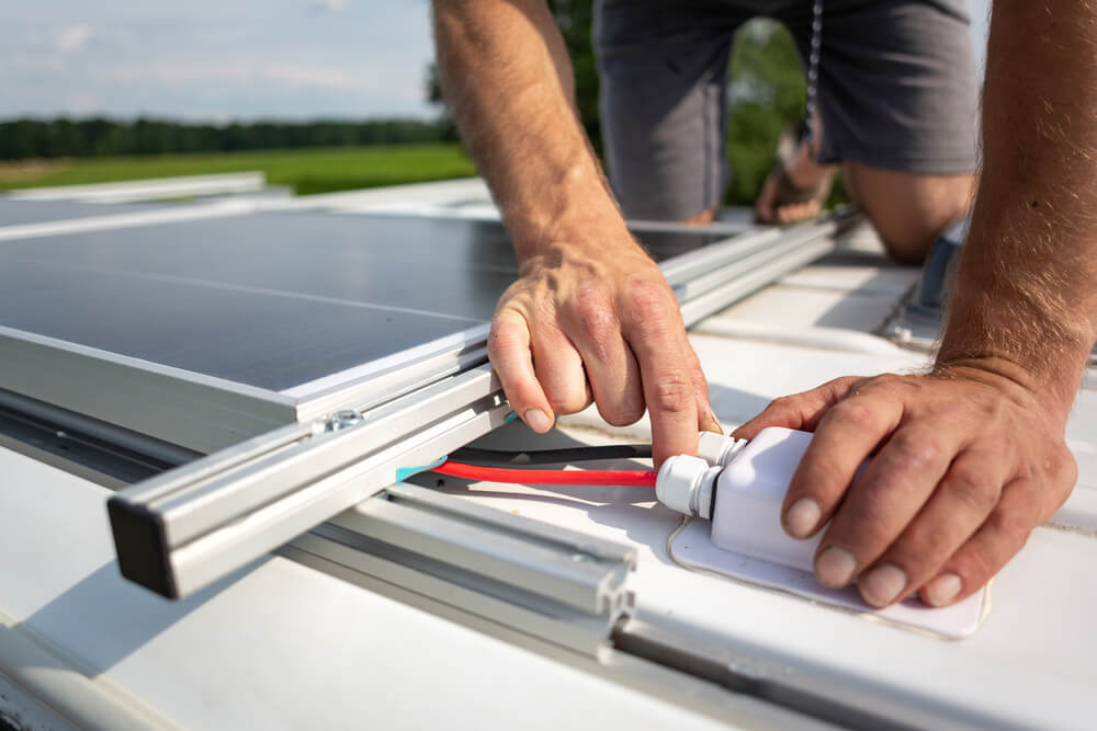 Caravan Technician installing a solar panel tothe top of a caravan